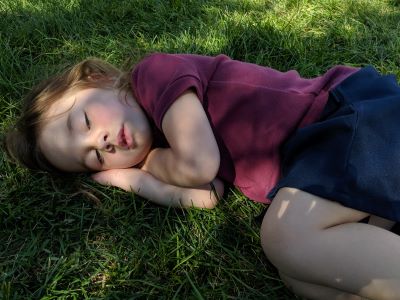 Preschool girl taking a nap on the grass
