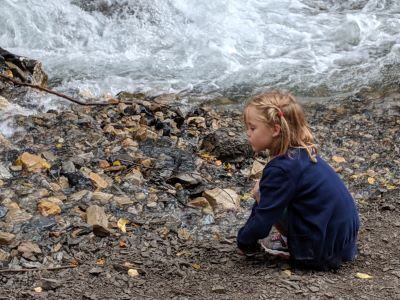 Little girl crouched by a river