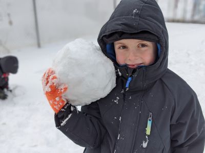 Preschool boy holding a large snowball