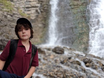 Boy standing near a waterfall