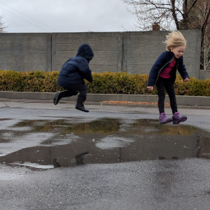 Preschool children jumping in puddles