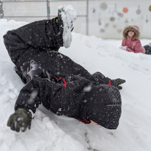 Child is sledding in the snow